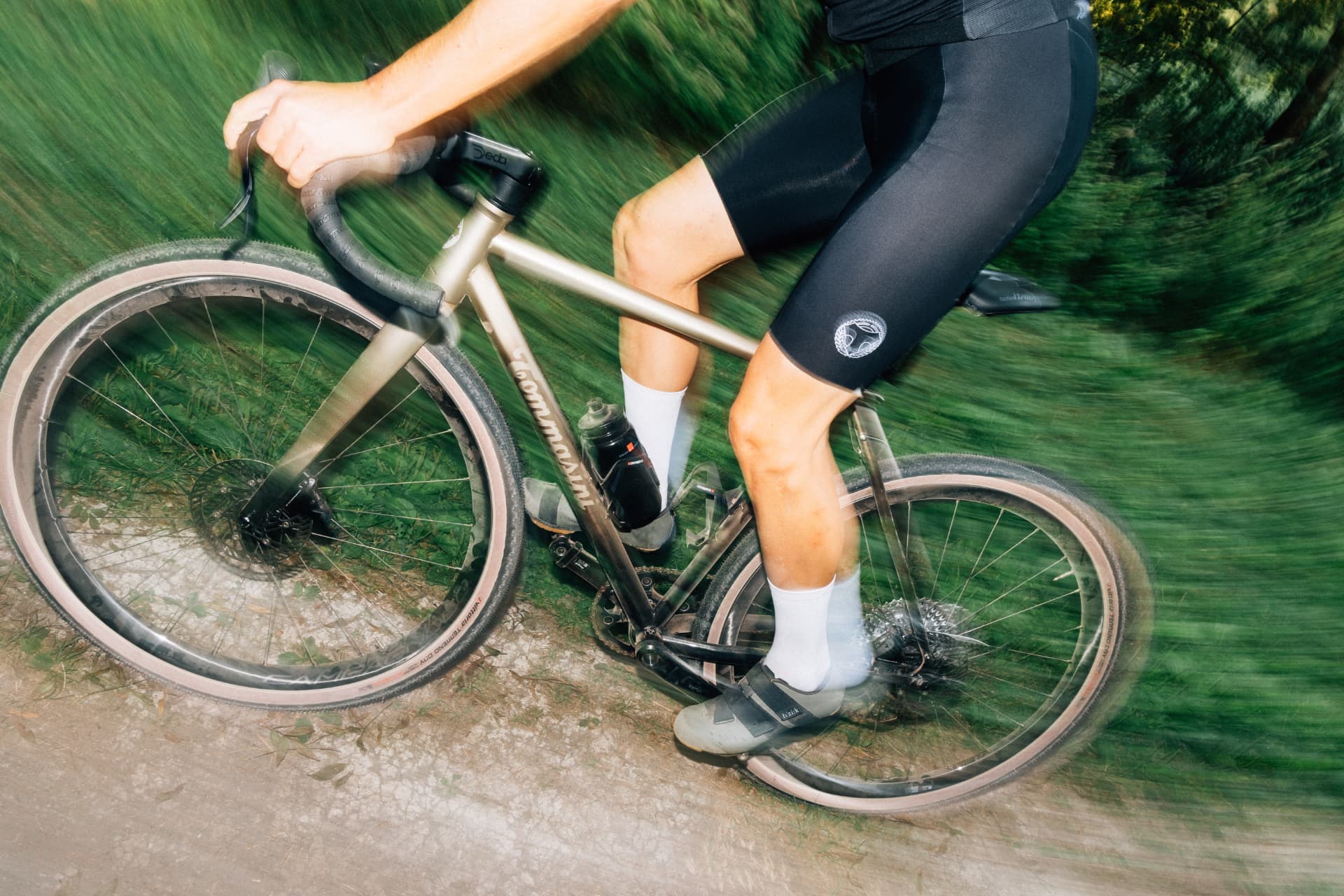 Dynamic action shot of a rider on the Tommasini Fire gravel bike through green countryside