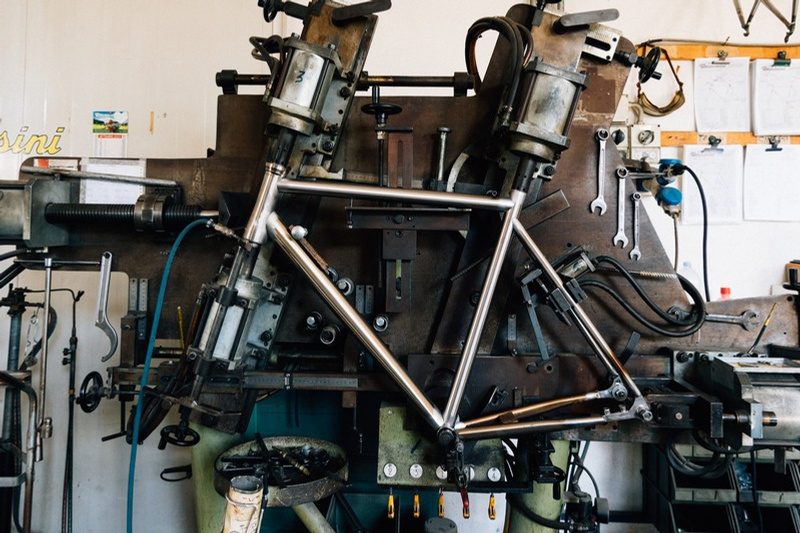 Raw titanium frame mounted on the alignment jig in the Tommasini workshop